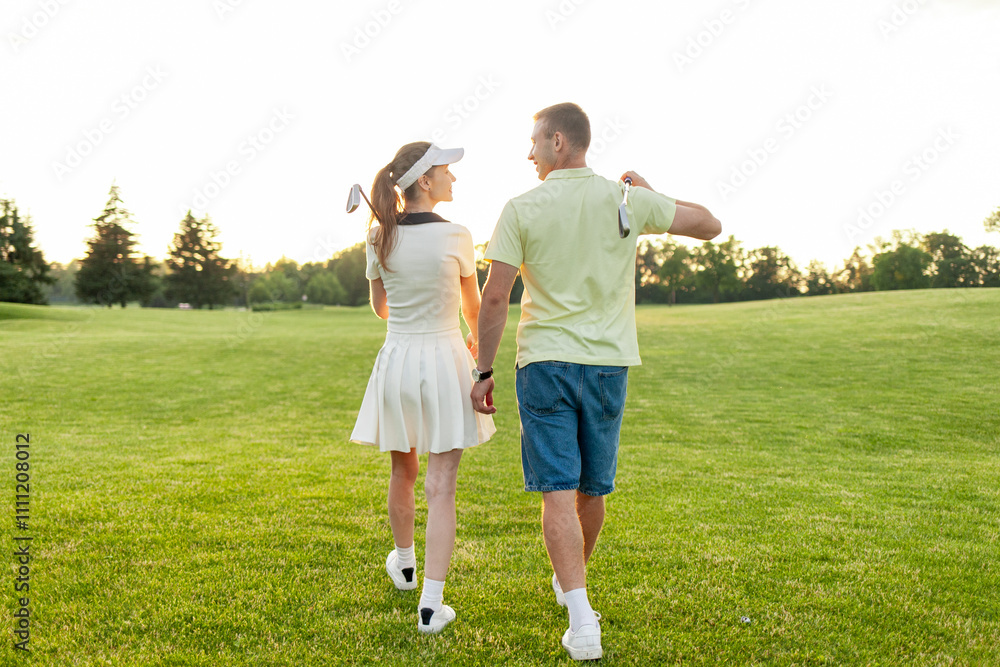 Obraz premium young sports couple in uniform playing golf together on field with lawn at sunset, woman with instructor practicing golf competitions and having active recreation