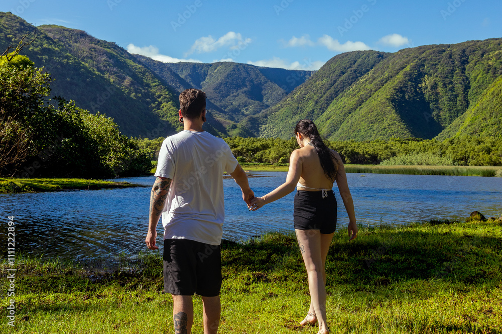 Naklejka premium Couple walking in Hawaii with mountains in the distance 