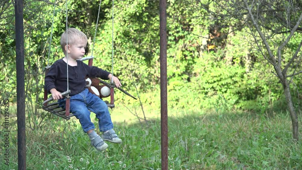 Little child with his teddy bear in a swing at countryside Little child with his teddy bear in a swing at countryside