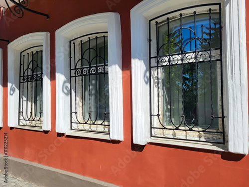 The facade is red with white windows and wrought iron grilles.