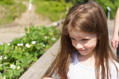 Beautiful cheerful girl in a white T-shirt having fun in the summer outdoors. Concept of an active, mobile, sincere child