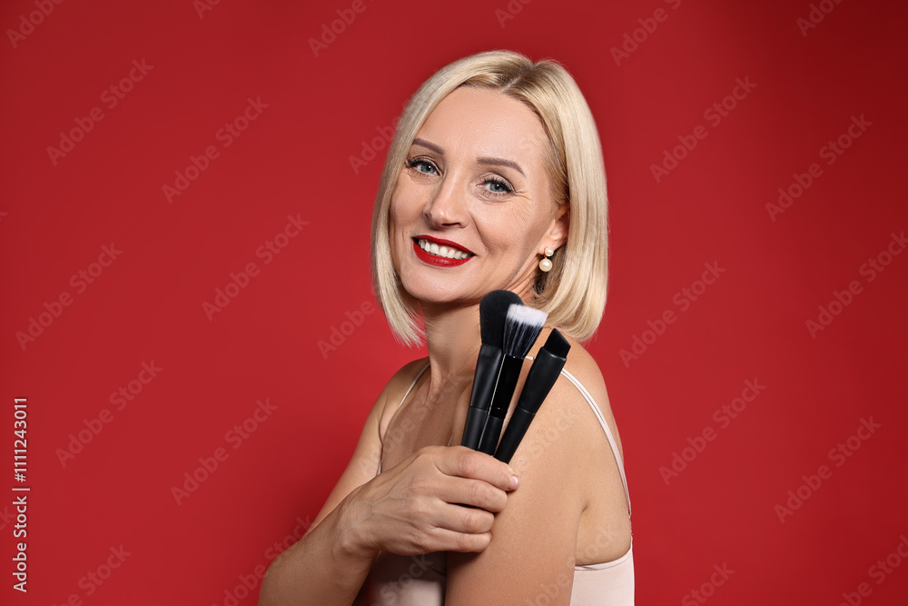 Smiling woman with different makeup brushes on red background Smiling woman with different makeup brushes on red background