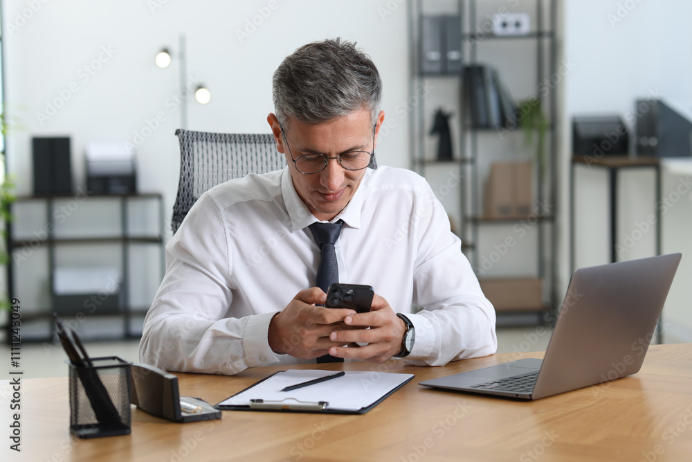 Businessman using smartphone at table in office Businessman using smartphone at table in office