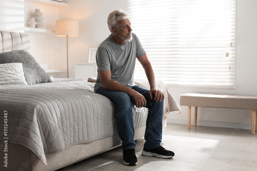 Lonely senior man sitting on bed at home Lonely senior man sitting on bed at home