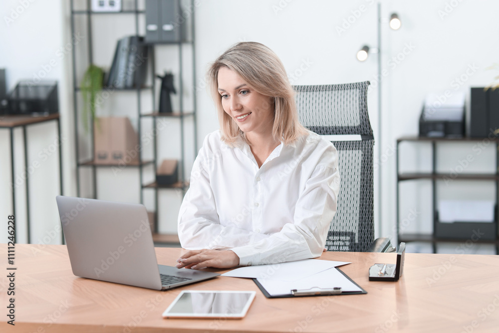 Businesswoman working on laptop at table in office Businesswoman working on laptop at table in office