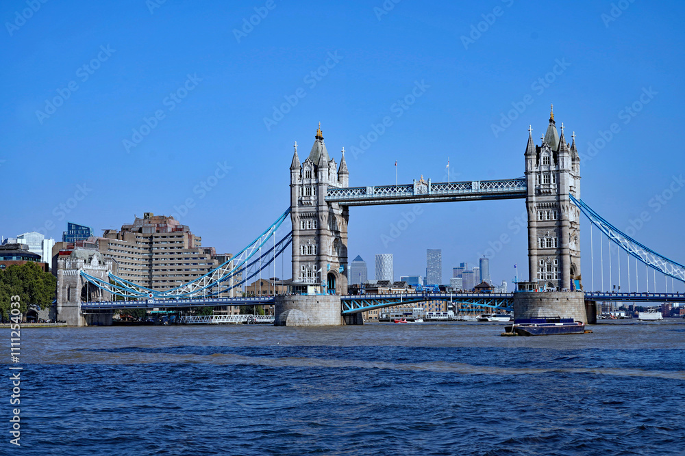 Obraz premium Tower Bridge on the Thames River, with distant office building at Canary Wharf in the background
