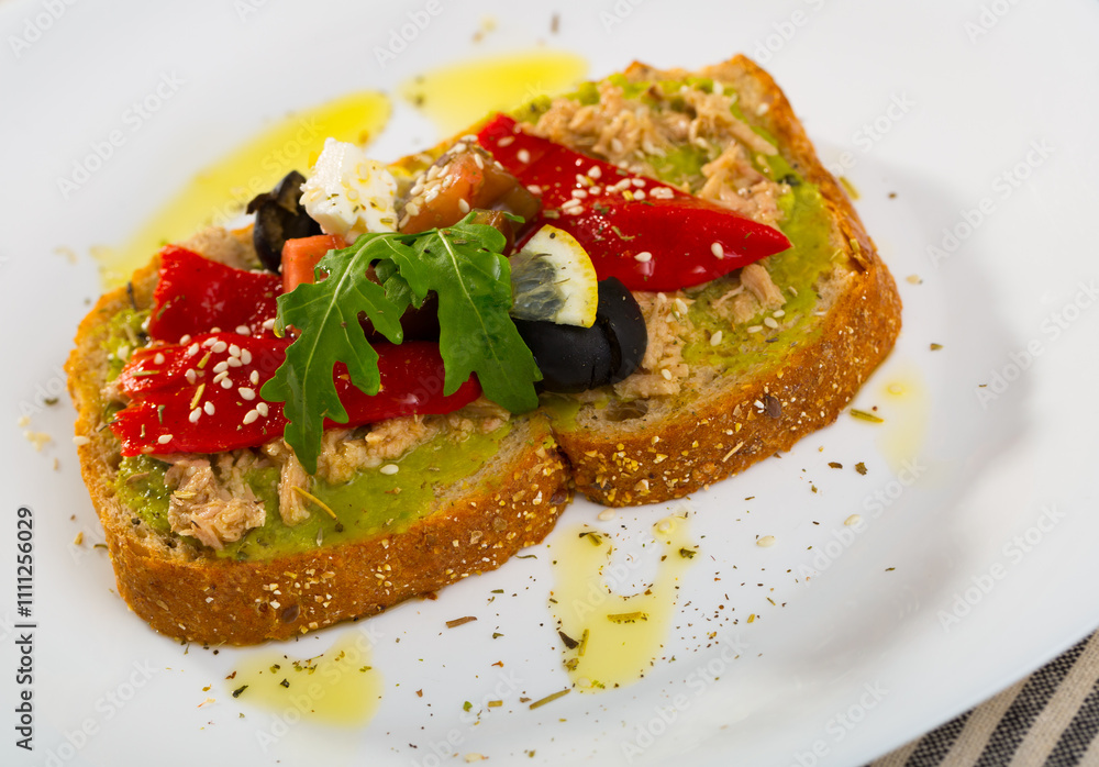 Healthy toasts with guacamole, canned tuna, feta cheese, fresh vegetables and lemon served on white plate.. Healthy toasts with guacamole, canned tuna, feta cheese, fresh vegetables and lemon served on white plate..
