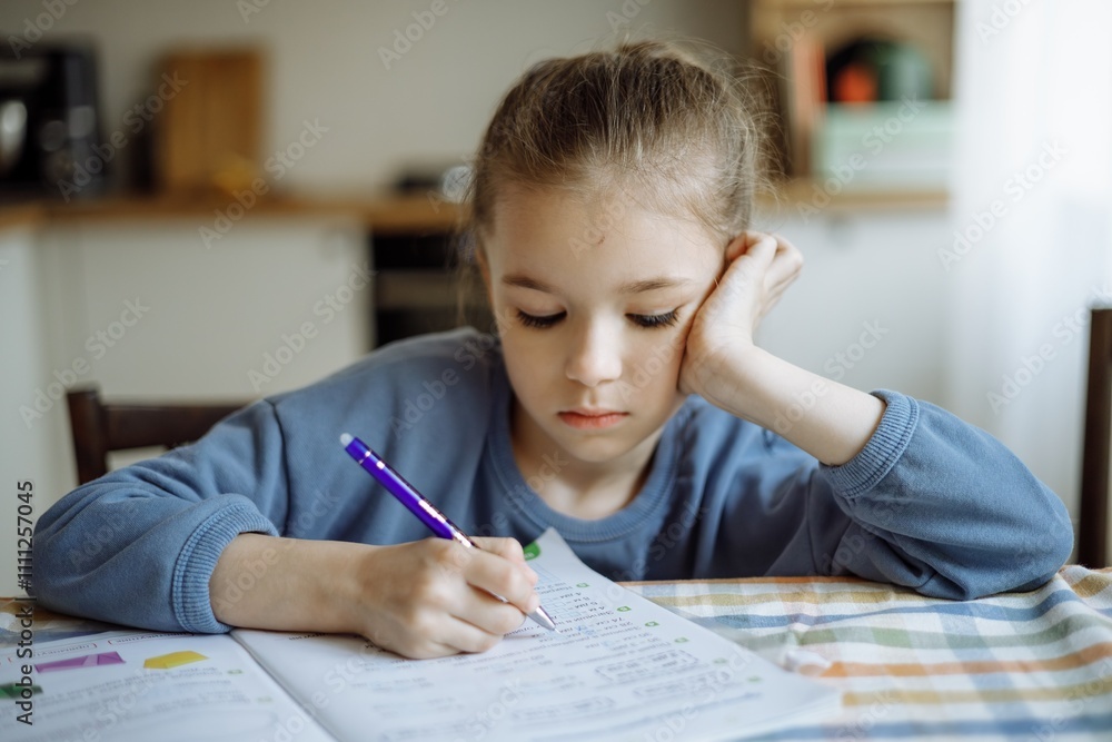 an independent 7-year-old girl doing her school homework at home in the kitchen an independent 7-year-old girl doing her school homework at home in the kitchen