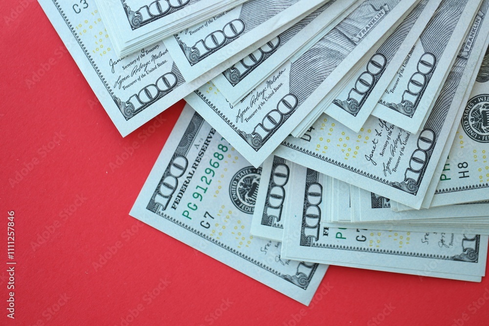 Big amount of hundred dollar bills in thick stack lies on bright red color paper background Big amount of hundred dollar bills in thick stack lies on bright red color paper background