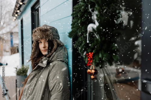 Happy woman near xmas house, enjoying the first snow. A young woman in a hat is having fun in the winter outdour Lifestyle. photo