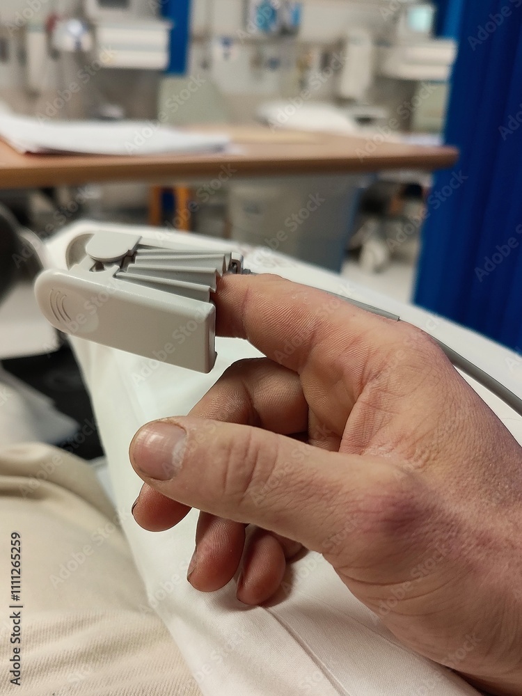 Obraz premium A hospital patient, with a device on the finger to monitor blood oxygen levels and heart rate. 