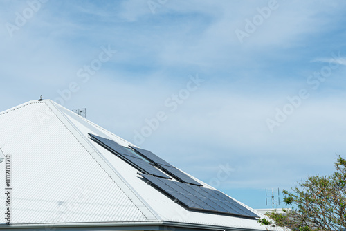 Rooftop solar PV photovoltaic panels on a white tin roof exposed to full sun blue sky photo