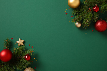 Christmas background with pine decor and vibrant baubles on green. Xmas greeting card template. Flat lay, top view, copy space.