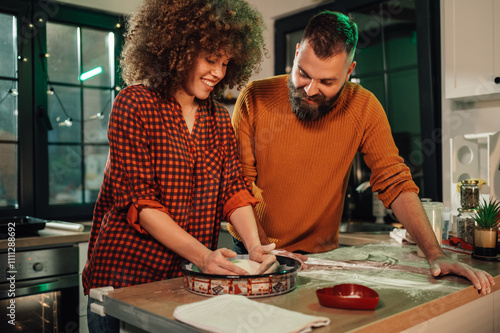 фотографія Happy couple preparing dough in kitchen for baking together