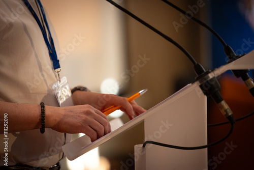 Fotografie focus sur un micro et les mains d'un orateur prononçant un discours à la tribune