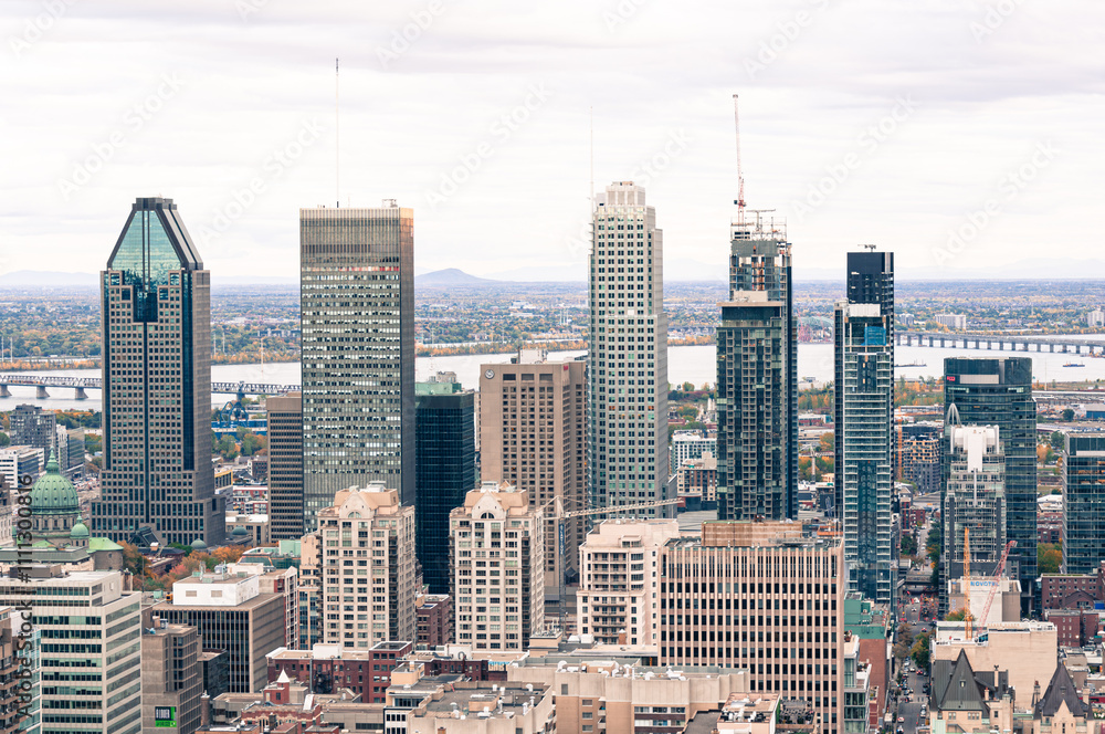 Fototapeta premium A vibrant view of Montreal’s downtown skyline with iconic skyscrapers, a backdrop of the St. Lawrence River, and a mix of modern and historic architecture.