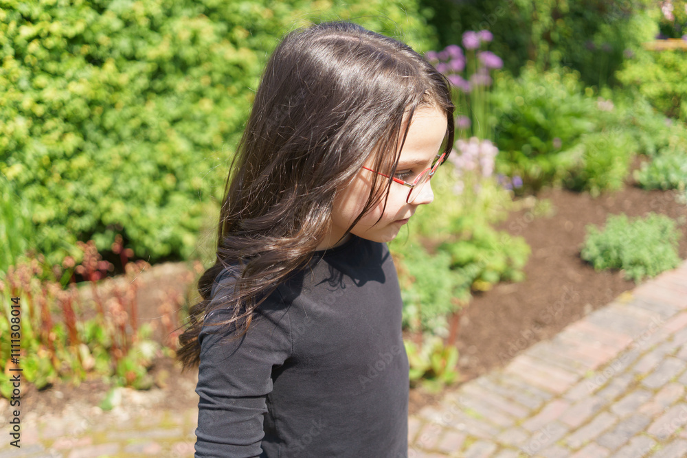Beautiful cheerful girl in glasses and black T-shirt having fun in the summer outdoors. Concept of active mobile sincere child Beautiful cheerful girl in glasses and black T-shirt having fun in the summer outdoors. Concept of active mobile sincere child