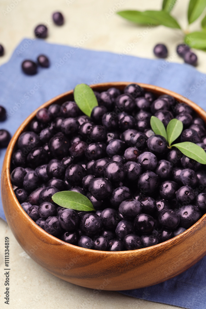 Ripe acai berries and leaves in bowl on grey table, closeup Ripe acai berries and leaves in bowl on grey table, closeup