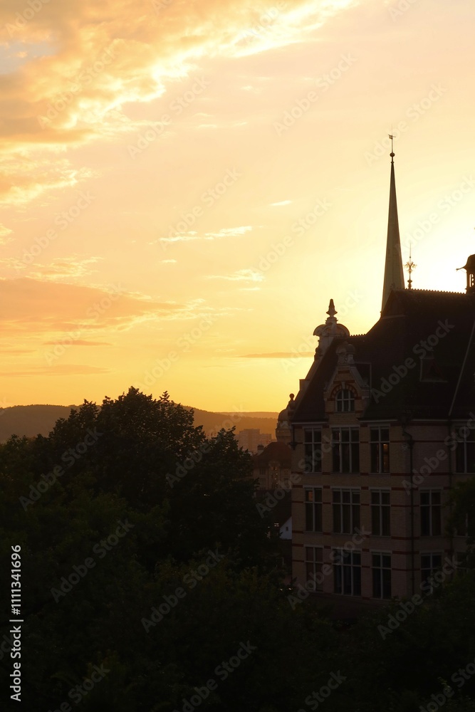 Obraz premium Historic Building Silhouette Against a Golden Sunset in Zurich Switzerland