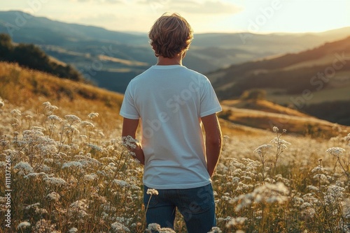 Man Stands in a Field of Flowers with Rolling Hills in the Distance at Sunset