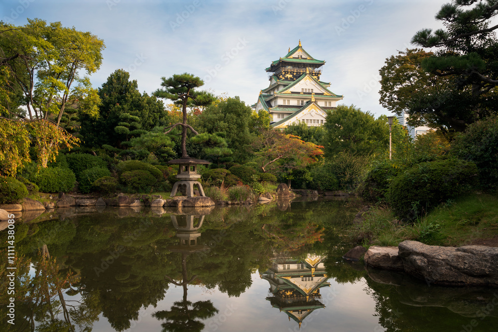 Osaka Castle with reflection in a pond in a Japanese garden on the castle grounds on a sunny autumn morning, Osaka, Japan Osaka Castle with reflection in a pond in a Japanese garden on the castle grounds on a sunny autumn morning, Osaka, Japan