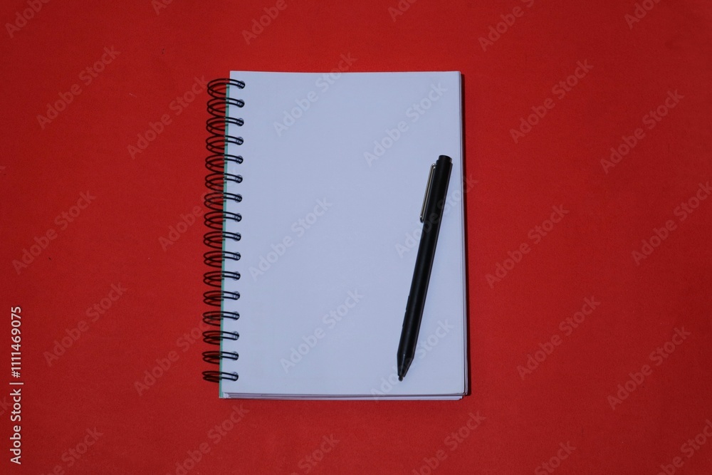 book with blank paper and pen, minimalist layout, isolated on red background. top view book with blank paper and pen, minimalist layout, isolated on red background. top view