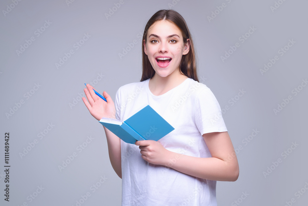 Young woman in white t-shirt holding notepad and pen, isolated over gray background. Student with notepad notebook. Positive student with notepad organizer. Young business woman writing on notepad. Young woman in white t-shirt holding notepad and pen, isolated over gray background. Student with notepad notebook. Positive student with notepad organizer. Young business woman writing on notepad.