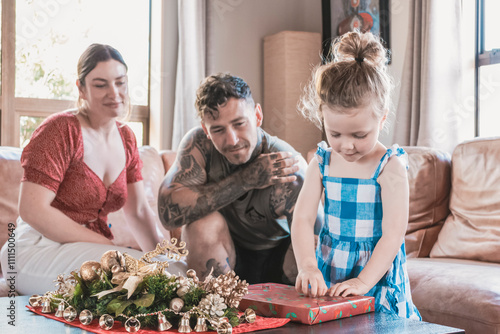 A young family spending quality time opening Christmas presents together.