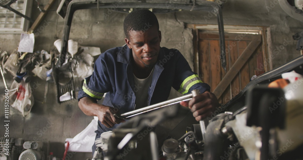 Φωτογραφία Front view of an African male car mechanic in a township workshop, repairing a c