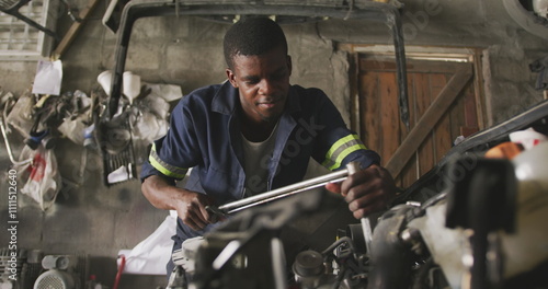Φωτογραφία Front view of an African male car mechanic in a township workshop, repairing a c