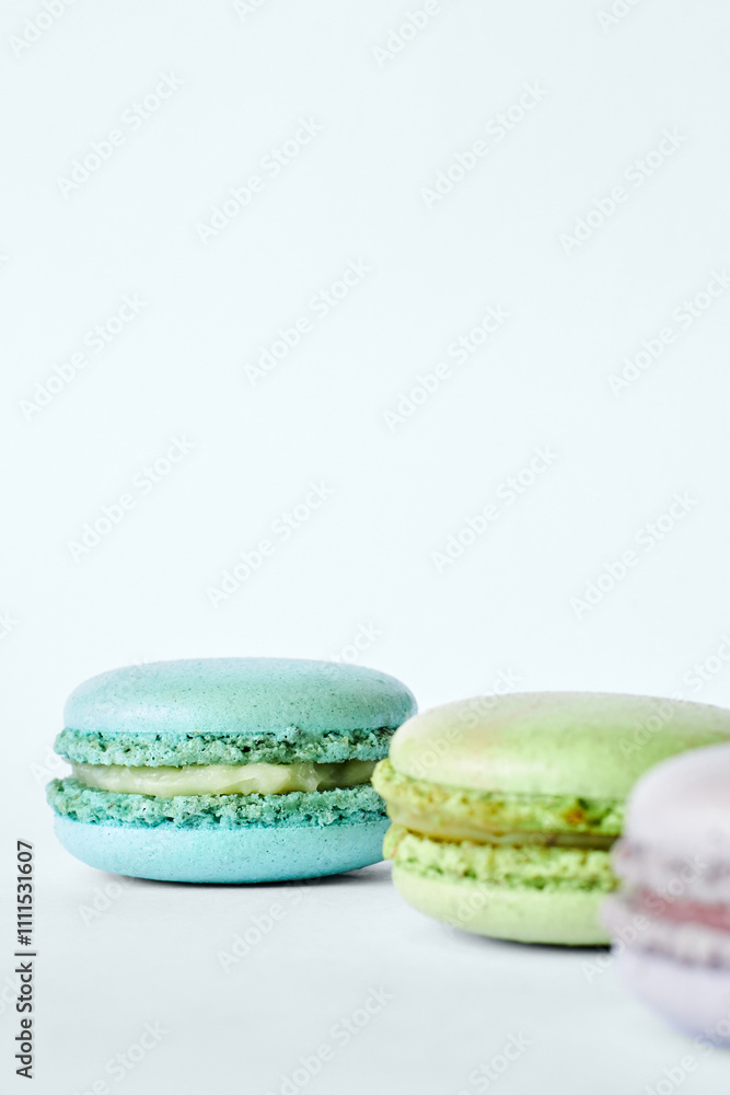 Three colorful French Macarons on gray background, cakes with different flavors, mint, apple, currant flavor. Homemade dessert, macaroons aquamarine, green, purple color. Selective focus, copy space Three colorful French Macarons on gray background, cakes with different flavors, mint, apple, currant flavor. Homemade dessert, macaroons aquamarine, green, purple color. Selective focus, copy space
