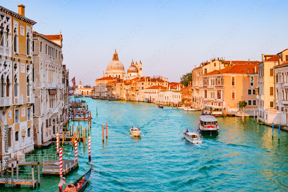 June 25, 2019. Venice, Italy. Beautiful view of traditional Gondola on famous Canal Grande with Basilica di Santa Maria della Salute in golden evening light at sunset in Venice, Italy.