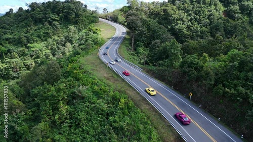 A sports car convoy is passing through the number three curve road in Nan province. It is a beautiful road that passes through the forest.