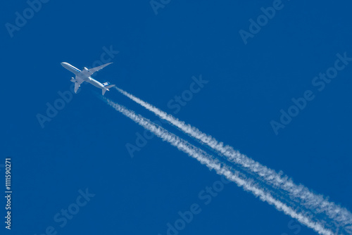 Commercial airplane with jet stream overhead view with blue background and vapour trail.