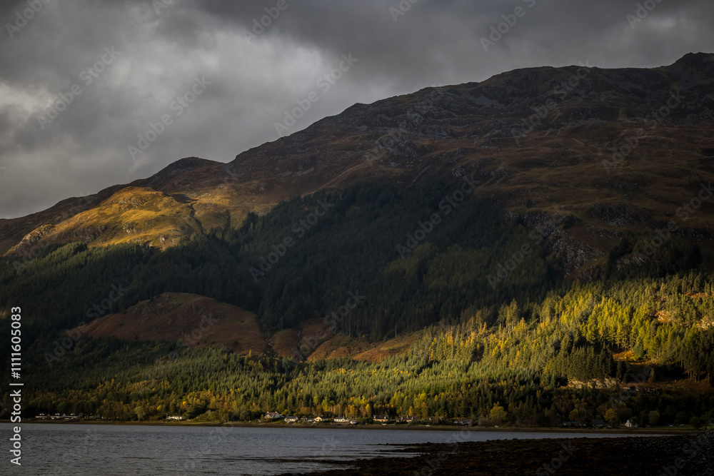 Storm clouds over the mountains with small patch of sunlight on tree line Storm clouds over the mountains with small patch of sunlight on tree line