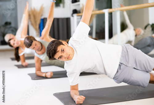 Slim young man practicing pilates exercises in training area during pilates classes photo