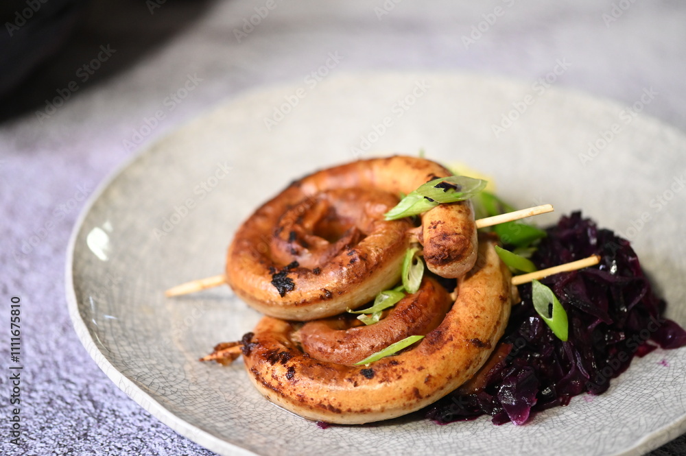 A beautifully plated dish featuring a grilled spiral sausage on a skewer, served with creamy mashed potatoes and braised red cabbage. A beautifully plated dish featuring a grilled spiral sausage on a skewer, served with creamy mashed potatoes and braised red cabbage.