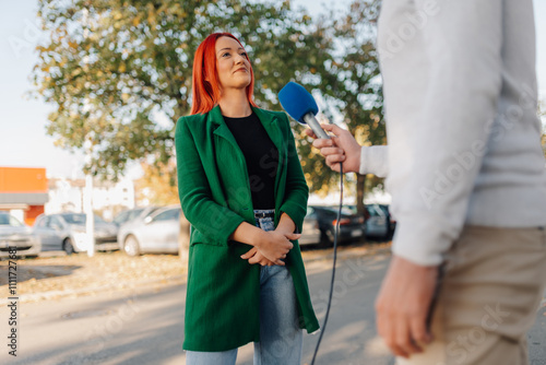 Journalist interviewing businesswoman with red hair holding microphone outdoors photo