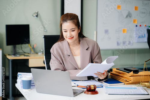 Confident lawyer working on legal analysis at a modern office desk, featuring scales of justice, a gavel