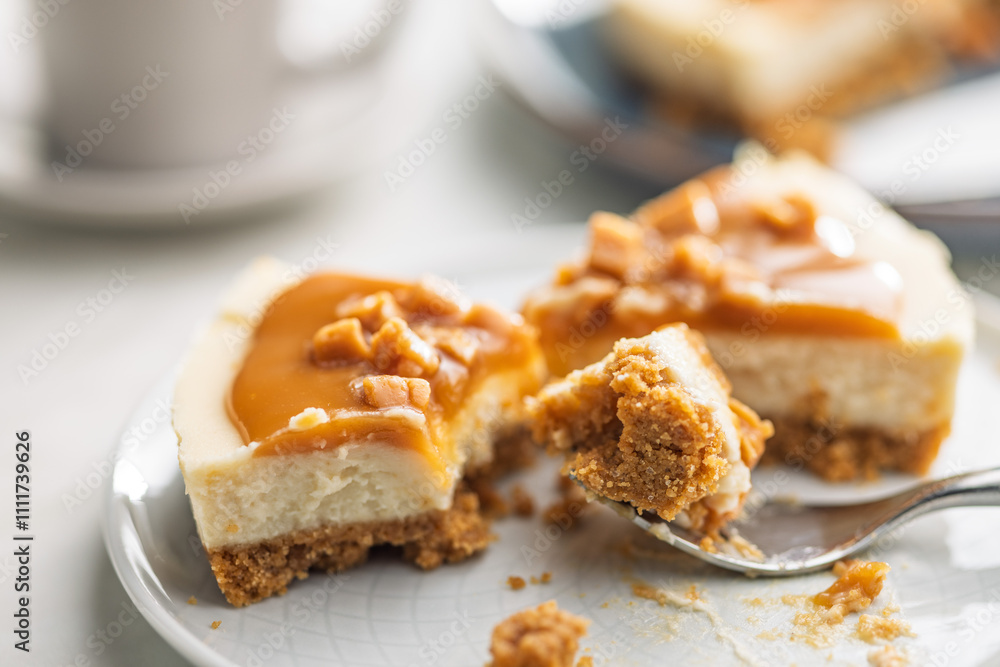 A cut piece of cheesecake with caramel topping on plate on kitchen table. A cut piece of cheesecake with caramel topping on plate on kitchen table.