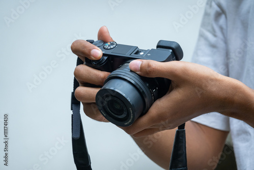 male asian photographer holding digital mirrorless camera with solid white backgroung