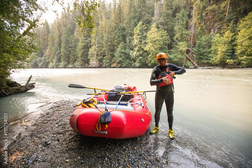 Raft guide puts on PFD before a whitewater rafting trip photo