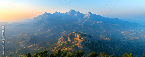 Majestic mountain range at sunrise, hazy valley below.