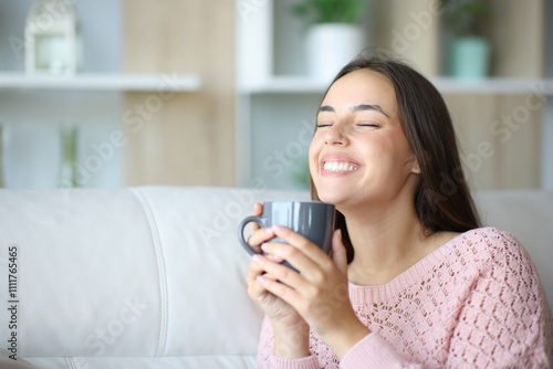 Happy woman smelling drink at home