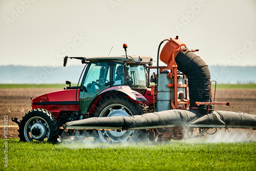 Serbia, Vojvodina Province, Tractor spraying herbicide in springtime wheat field photo