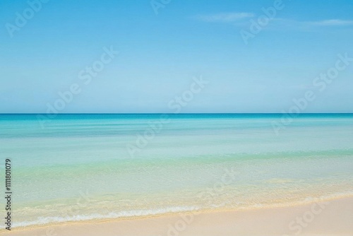 Serene beach with gentle waves under a clear blue sky.