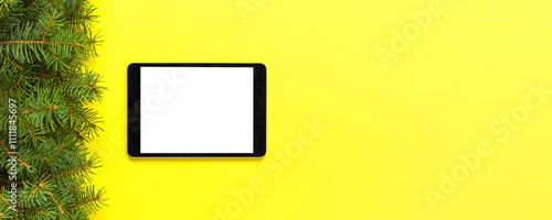 Tablet with blank screen on the yellow pastel color background. Top view with christmas decor