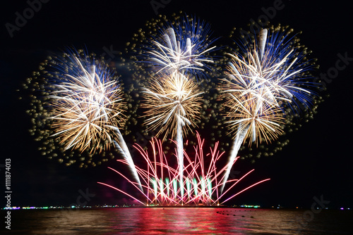 Multi-colored fireworks are launched in the middle of the sea from a large steel ship .