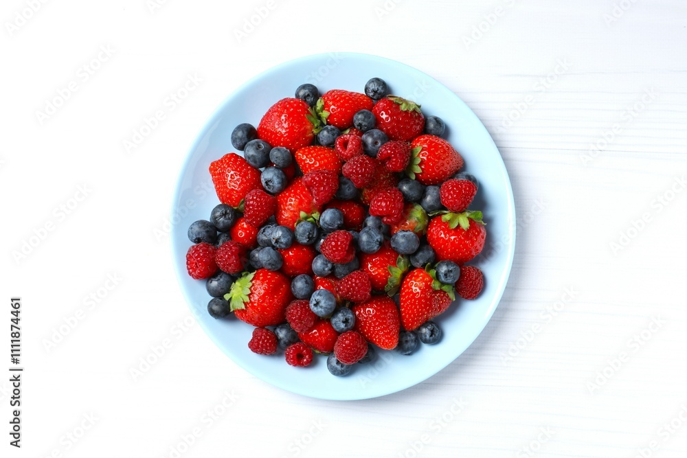 Different fresh ripe berries in bowl on the table, top view Different fresh ripe berries in bowl on the table, top view