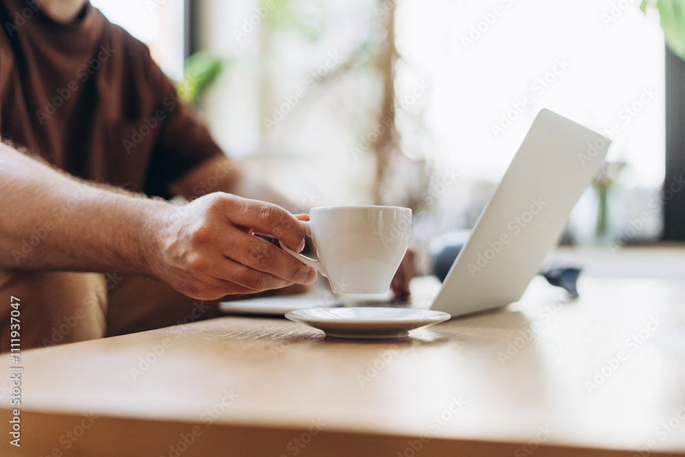 Busy manager, programmer using laptop, writer typing on keyboard, holding cup with coffee Busy manager, programmer using laptop, writer typing on keyboard, holding cup with coffee